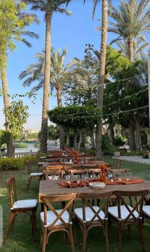 a group of wooden tables and chairs with palm trees at Villa in El-Manâkh