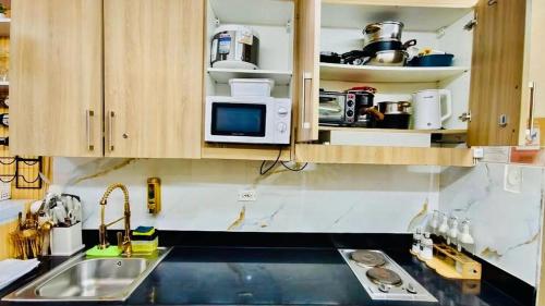a kitchen with a sink and a microwave at Hotel De Rama Unit 1230 near MOA & NAIA in Manila