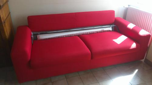 a red couch is sitting in a room at Maison entre Cherbourg et Mont Saint Michel in Saint-Aubin-du-Perron