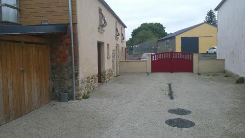 an alley with a red gate and a building at Maison entre Cherbourg et Mont Saint Michel in Saint-Aubin-du-Perron