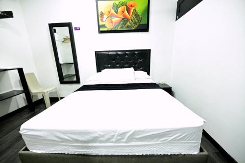 a bedroom with a white bed and a mirror at Hotel Puerta del Sol de Uraba in Apartadó