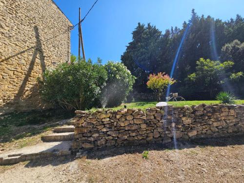 a garden with a stone wall and a fountain at MAS PROVENCAL A FLANC DE COLLINE in Bollène