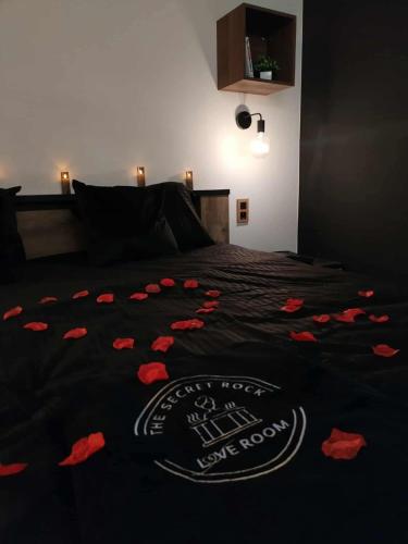 a bed with a black blanket with red flowers on it at Secret Rock - Jaccuzi privé in La Roche-en-Ardenne