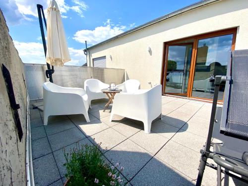 a patio with white chairs and an umbrella at Luxuriöses Penthouse mit Parkplatz zentral in Eltville in Eltville