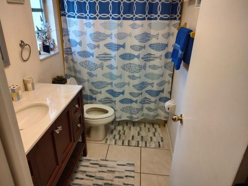 a bathroom with a toilet and a shower curtain at TheTotal Florida life style heated pool 5 bedrooms in Punta Gorda