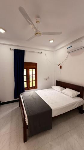 a bedroom with a large bed with a blue curtain at Nachchi Sweet Beach Stay in Nilaveli