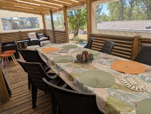 a dining room with a table and chairs on a deck at Mobil home Apollon Riviera in Saint-Papoul