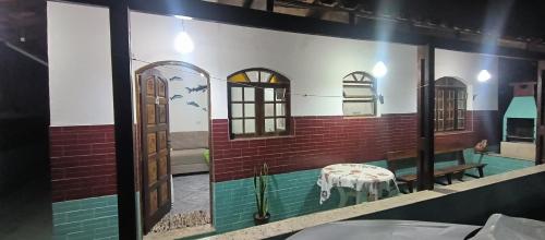 ein Raum mit einer Wand mit Fenstern und einem Tisch in der Unterkunft Casa de Praia Bertioga-Costa do Sol Guaratuba in Bertioga