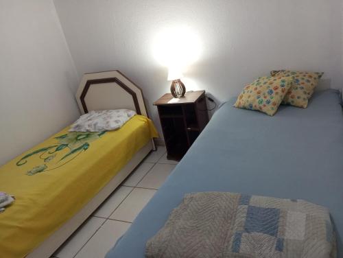 two beds in a room with a lamp on a night stand at Riviera imóveis in Campo Grande