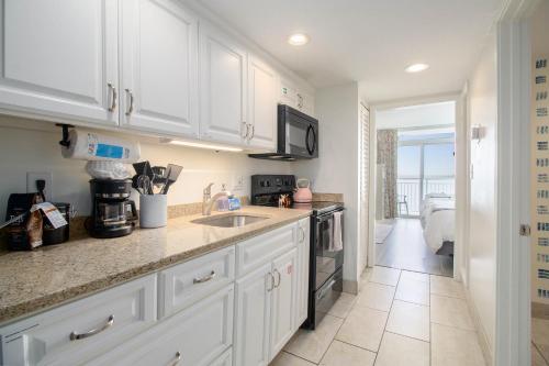 a kitchen with white cabinets and a counter top at Beachfront Bliss! Ocean Views, Lazy River, Pools, Hot Tubs, Near the Boardwalk in Myrtle Beach