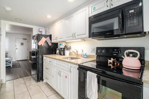 a kitchen with white cabinets and black appliances at Beachfront Bliss! Ocean Views, Lazy River, Pools, Hot Tubs, Near the Boardwalk in Myrtle Beach