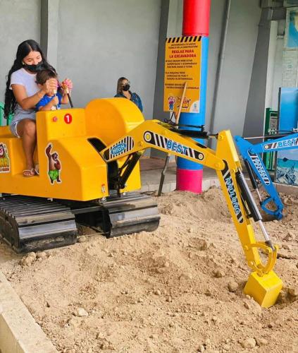 a woman and a child riding on a toy machine at Hotel Vista Verde in Yauco