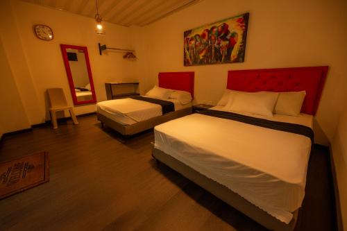 a hotel room with two beds and a mirror at Hotel Puerta del Sol de Uraba in Apartadó