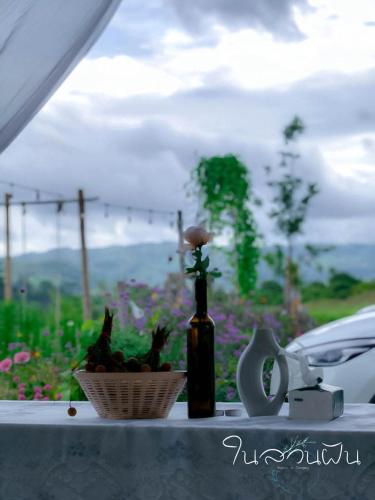 a table with a bottle and a basket of flowers at Safari Camping Type in Ban Thung Samoe