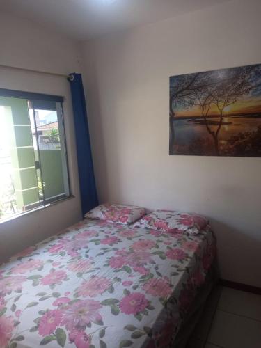 1 Schlafzimmer mit einem Bett mit einer Blumendecke und einem Fenster in der Unterkunft Quartos palhoça in Palhoça