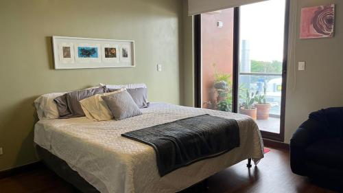 ein Bett mit einer Decke darauf in einem Schlafzimmer in der Unterkunft Apartamento bellamente decorado en la zona 10 in La Aurora