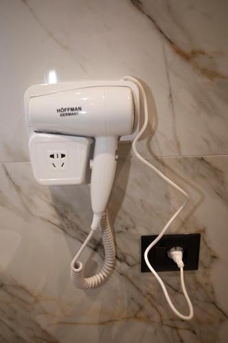a white hair dryer is plugged into a wall at Villa Klaus Hotel in Tirana