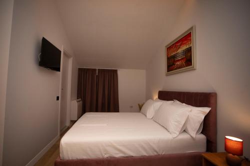 a bedroom with a white bed and a television at Villa Klaus Hotel in Tirana