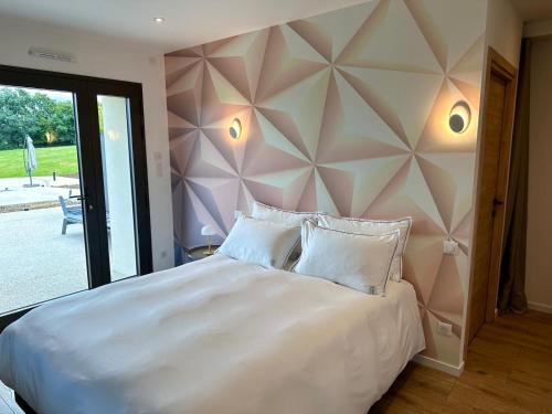a bedroom with a large white bed with a wall at Les Rubys, spas privatifs in Tarcenay