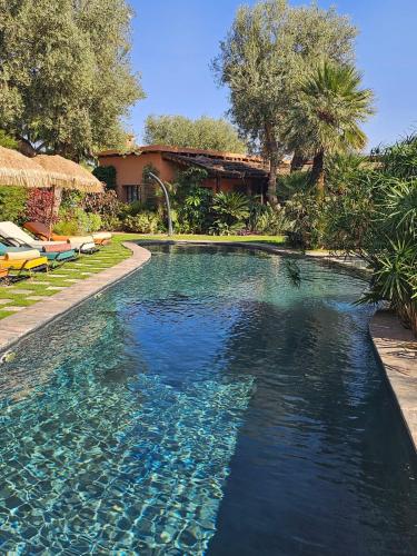 a swimming pool with blue water in front of a house at oasis de paix in Aït Amara