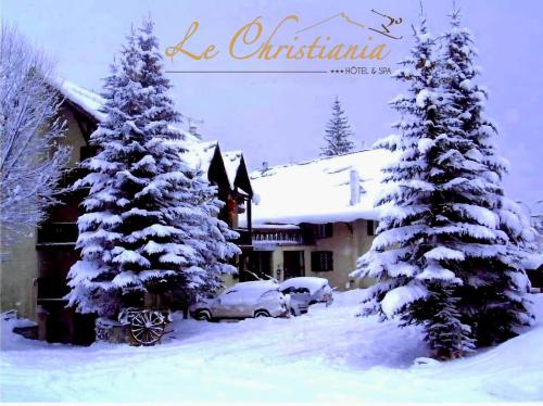 two christmas trees covered in snow in front of a building at Logis Hôtel et Spa Le Christiania in La Salle Les Alpes