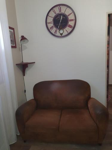 une horloge suspendue sur un mur au-dessus d'un canapé dans l'établissement Appart 2 chambres intramuros climatisé, à Avignon