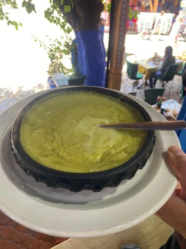 a person holding a bowl of soup on a plate at Dar Larbi in Chefchaouene