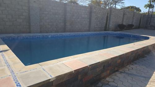 a swimming pool with a brick retaining wall at Chila Villa in Chilanga