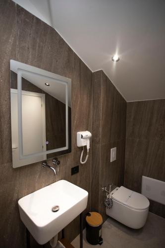 a bathroom with a sink and a mirror and a toilet at Villa Klaus Center Hotel in Tirana