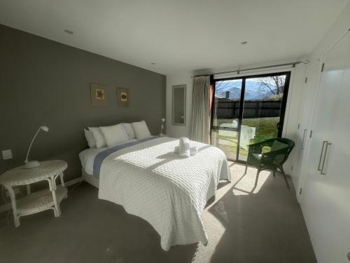 a bedroom with a bed and a chair and a window at Chartres Retreat in Arrowtown