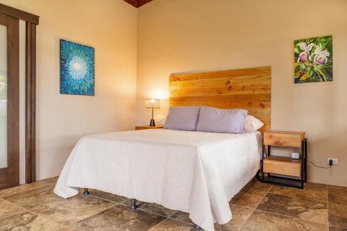 a bedroom with a white bed with a wooden headboard at Getaway & Ocean Breeze - Secluded & Natural Charming - 2 bedrooms in Barú