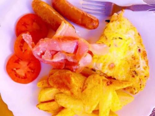 a plate of breakfast food with eggs tomatoes and a pickle at Caster two bedrooms apartment jkia in Nairobi