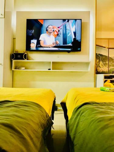 a room with two beds and a tv on a wall at Hotel De Rama Unit 5115 near MOA and NAIA in Manila
