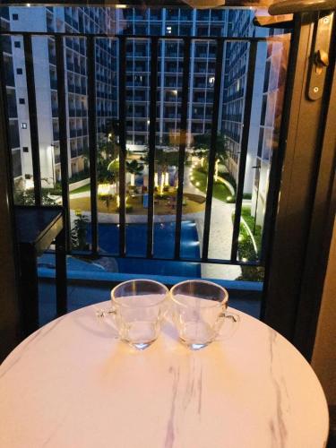 two glasses sitting on a table with a view of a city at Hotel De Rama Unit 5115 near MOA and NAIA in Manila