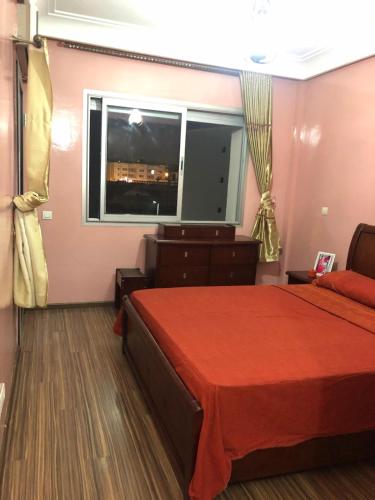 a bedroom with a red bed and a window at Apartment Galia Mohammedia in Mohammedia