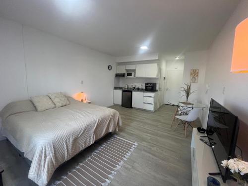 a white bedroom with a bed and a kitchen at L&M Suite Monoambiente in Belén de Escobar
