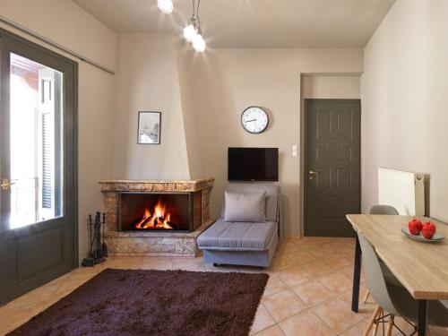 a living room with a fireplace and a chair and a table at Luxury Studios & Cozy Apartments by White Hills in Arachova