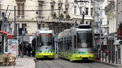 Dos tranvías verdes y plateados en una calle de la ciudad en Great apartment avec stationnement, en Saint-Étienne