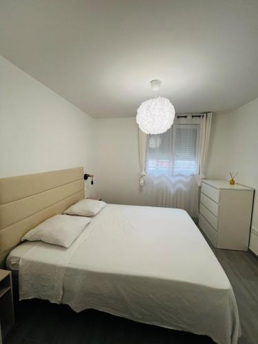 a bedroom with a large white bed and a chandelier at Appartement cosy prêt de Paris Cdg, Astérix , Parc des expositions et Centre de formation CAMAS in Tremblay-En-France