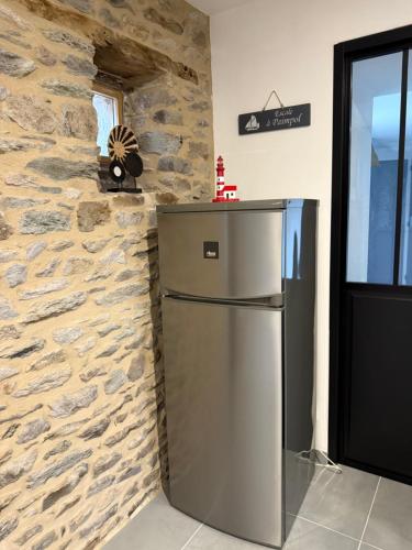 a refrigerator in a kitchen with a stone wall at Ty Kermaudez in Paimpol