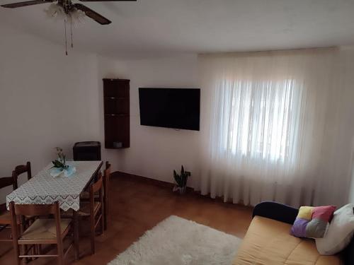 a living room with a table and a television on the wall at Family & Friends - First floor - South West wing - Fully equipped with view - 15 minutes drive by car to the seaside in Galtellì