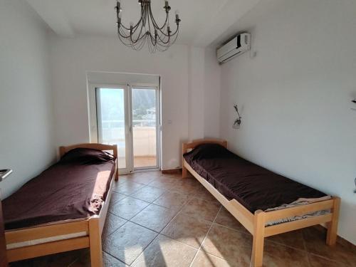 two beds in a room with a chandelier at Simple Stay in Buljarica