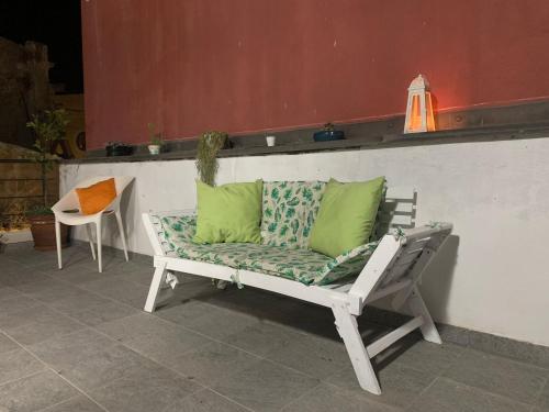 a white bench with green pillows on a patio at Apa Sicula in Avola