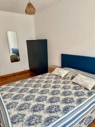 a bedroom with a large bed with a blue headboard at Canalentin - proche Canal du Midi in Castelnaudary