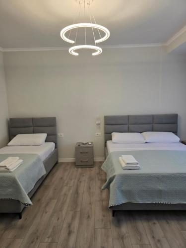 a bedroom with two beds and a chandelier at Fraj Holiday Homes Pogradec in Pogradec