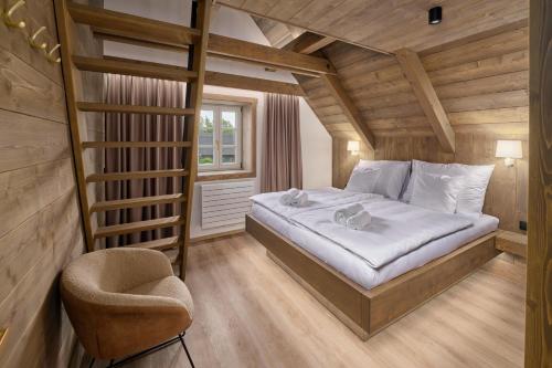 a bedroom with a bed and a chair in it at Chalupy Raz Dva in Roprachtice