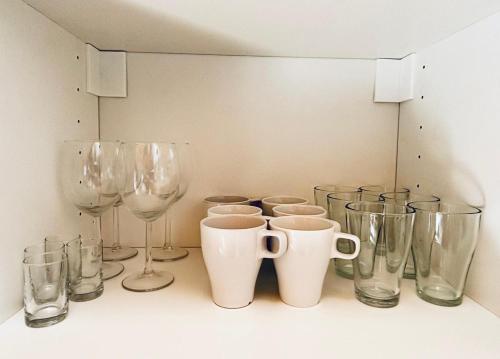 a row of glasses and wine glasses on a shelf at Leśna Przystań in Pobierowo