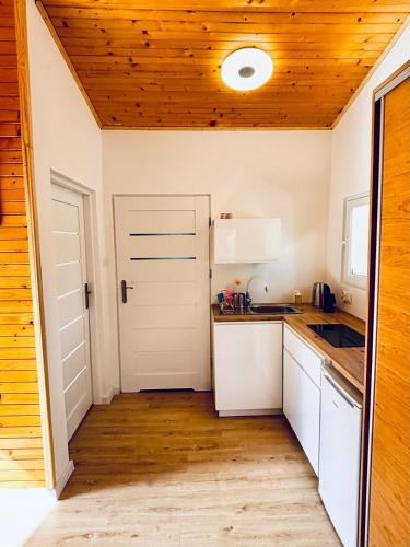 a kitchen with white cabinets and a wooden ceiling at Leśna Przystań in Pobierowo
