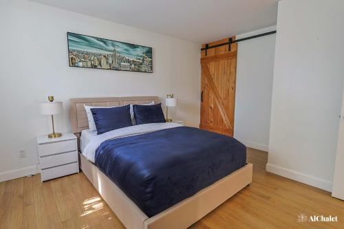 a bedroom with a bed with blue sheets and a wooden door at Artiste B - Esquisse Moderne in Wendake