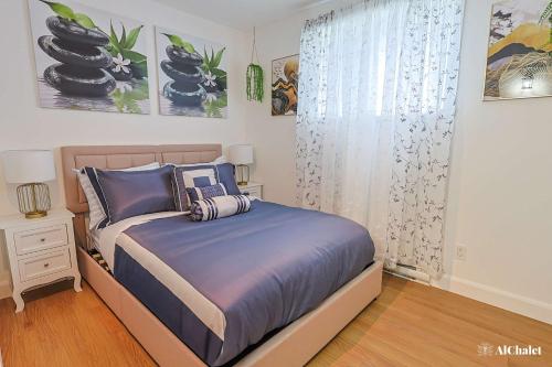 a bedroom with a bed with blue sheets and a window at Artiste B - Esquisse Moderne in Wendake